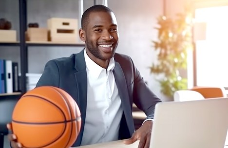 Smiling professional with a basketball at an office desk, representing HBCU Sports Management Programs excellence.