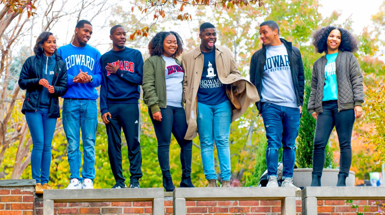 Smiling Howard University students handout together on campus wearing their winter Howard Bison paraphernalia during the fall semester.