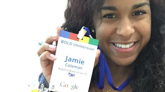 Jamie Coleman smiles while holding up her Google badge during her summer internship.