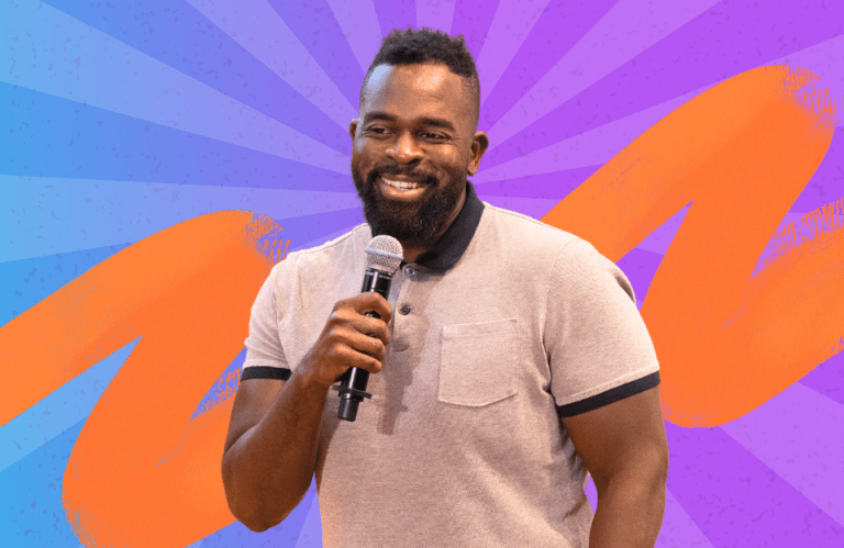 Busayo Ogunsanya smiling while holding a microphone, symbolizing his transition from an accountant to a tech entrepreneur.