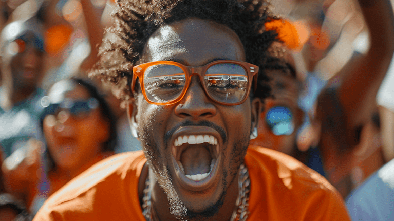 Excited cheering Black college football fan with orange glasses at HBCU Football Classics 2024.