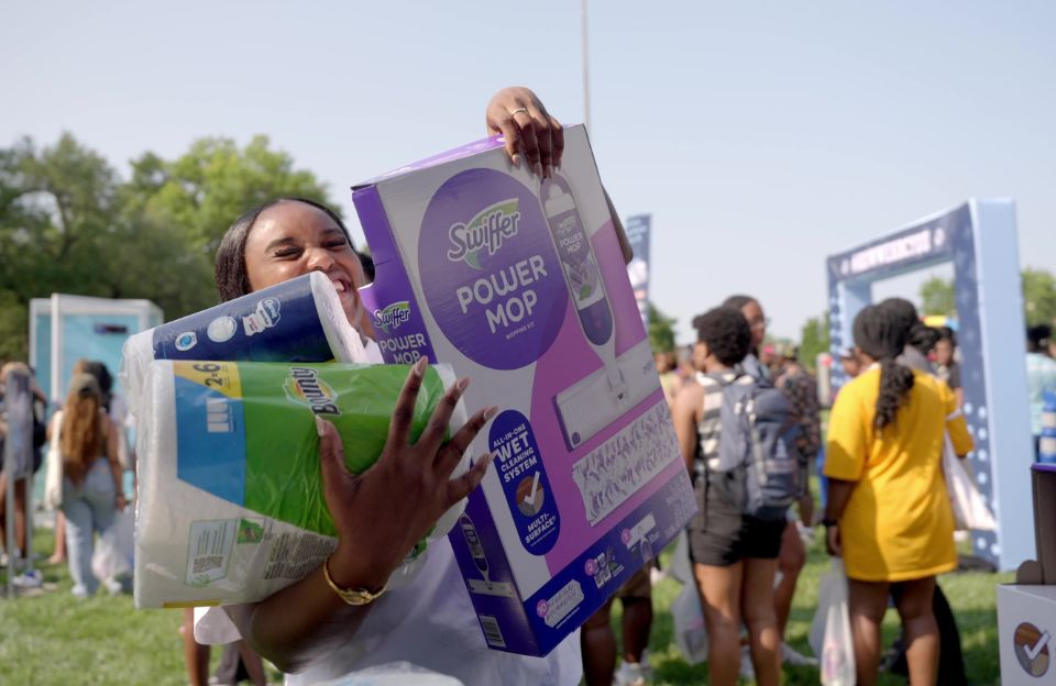 A student at Howard University smiles while holding Swiffer Power Mop and paper towels during P&G’s #HowWeHBCYOU product giveaway.